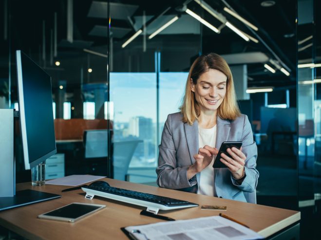 Successful woman working in a modern office on a computer, businesswoman uses the phone, social networks, online browsing